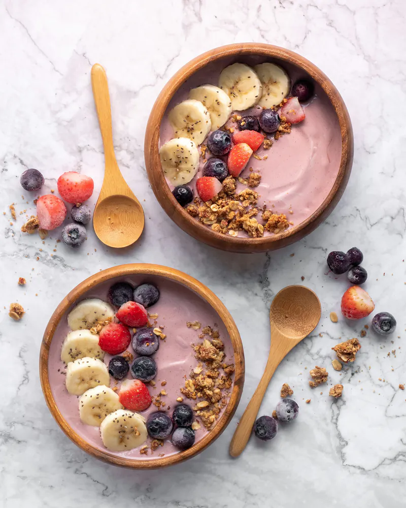 Muz, çilek ve yaban mersiniyle hazırlanmış iki smoothie kasesi