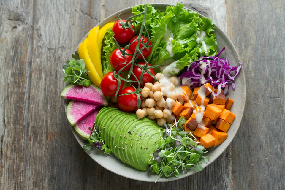 Avokado, nohut, tatlı patates ve yeşilliklerle hazırlanmış renkli salata kasesi